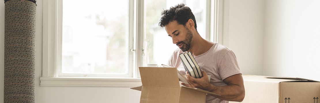 A seated man places books in a cardboard box